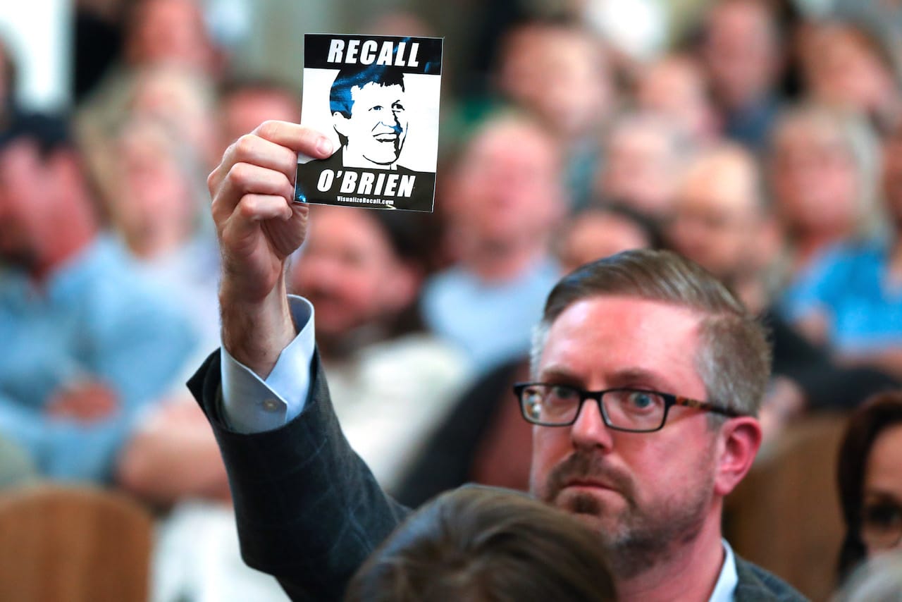 Man holds recall mike o'brien sticker
