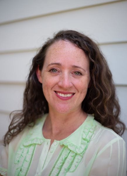 White woman with curly hair smiling