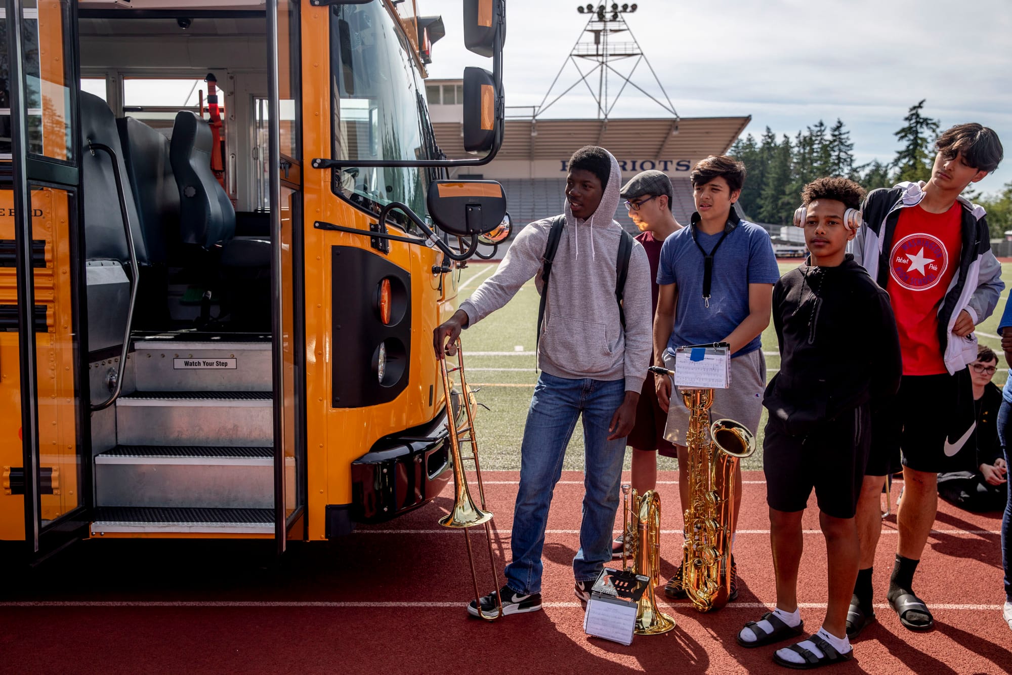 Students listen to speakers next to the first electric school bus in Washington state during an event with Governor Jay Inslee at Franklin Pierce High School in Tacoma on June 17, 2019. (Photo by Dorothy Edwards/Crosscut)