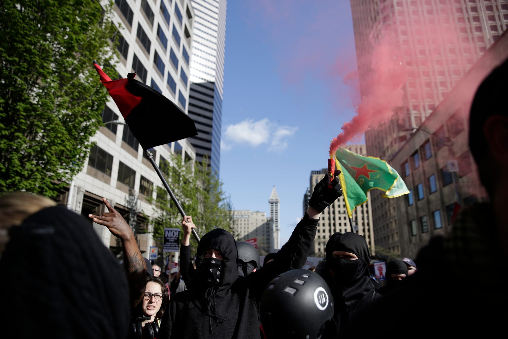  Individuals dressed in black, who wished to remain anonymous, carry a smoke flare and march in the annual May Day March for Workers and Immigrant Rights in Seattle, May 1, 2018.