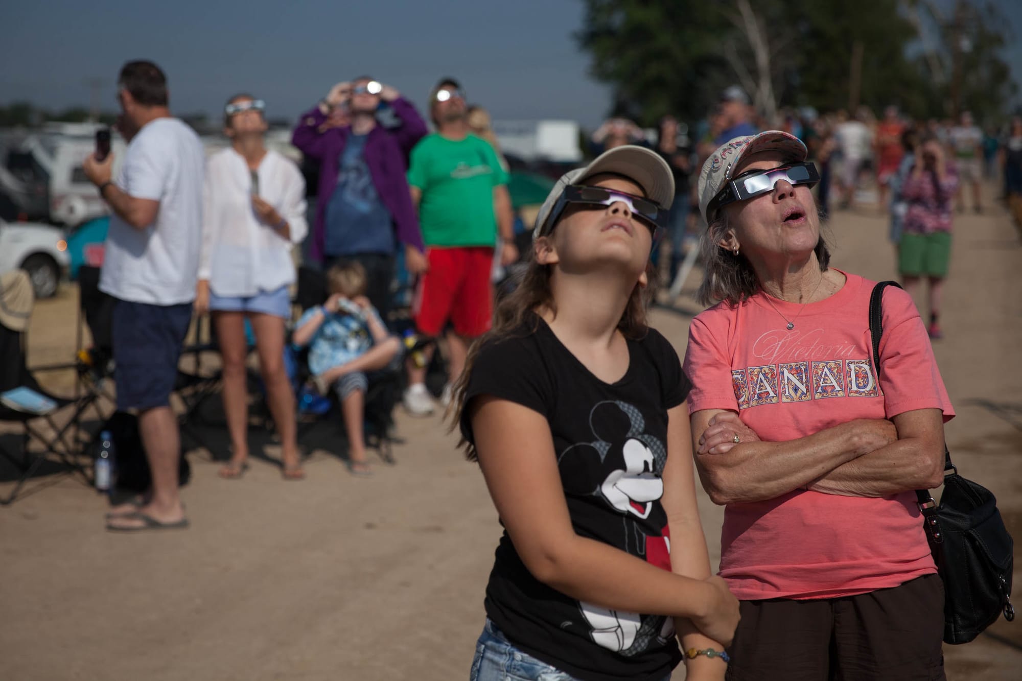 Two spectators look up at eclipse with eclipse glasses