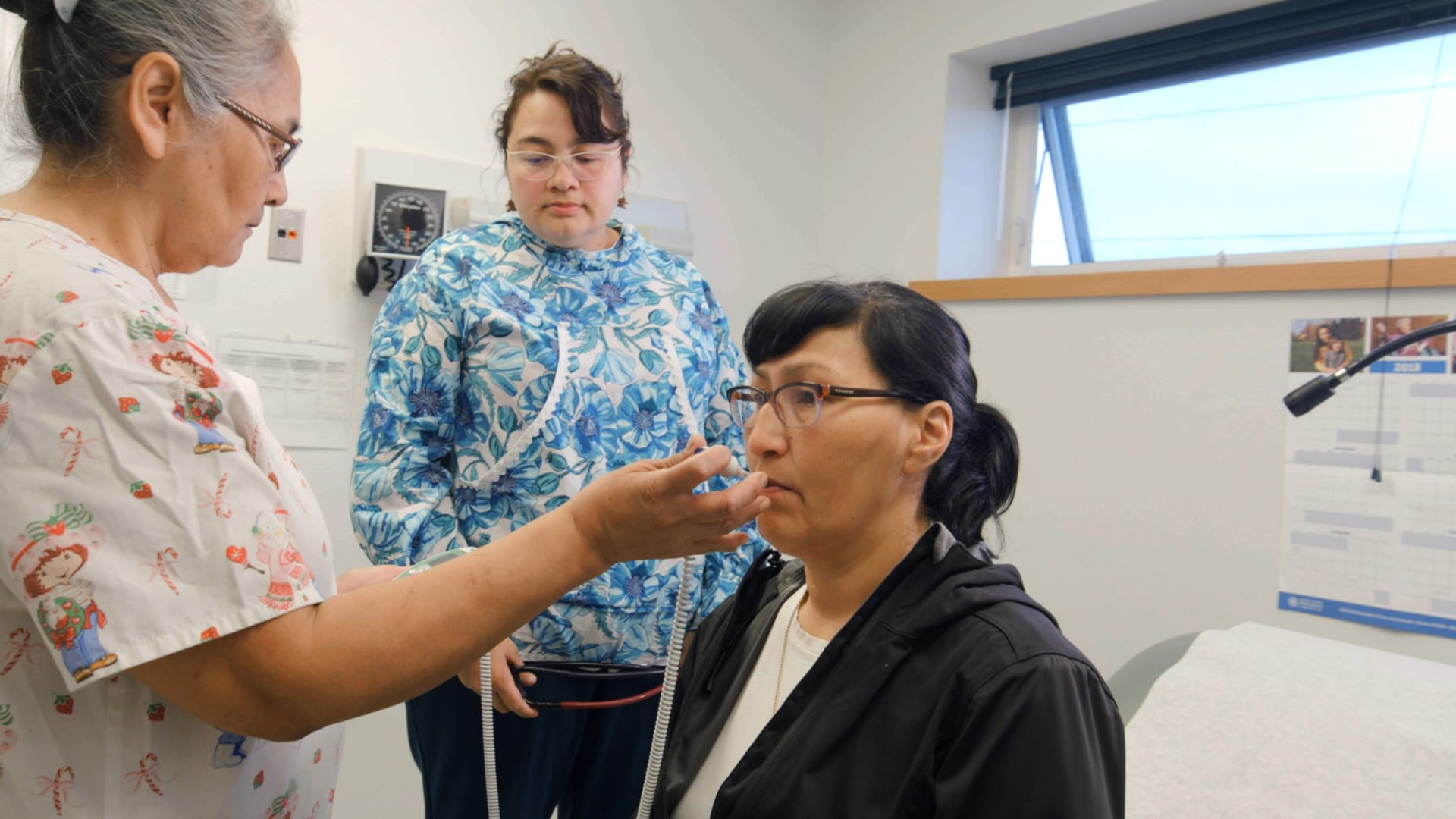 Two health workers do a simple exam on a patient