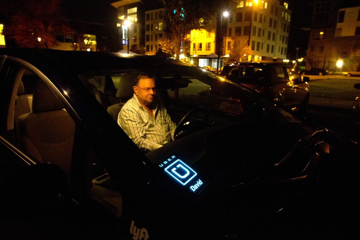 Mayor David Baker sits in his Prius in the parking lot of Kenmore City Hall with an Uber light illuminated on his dashboard.