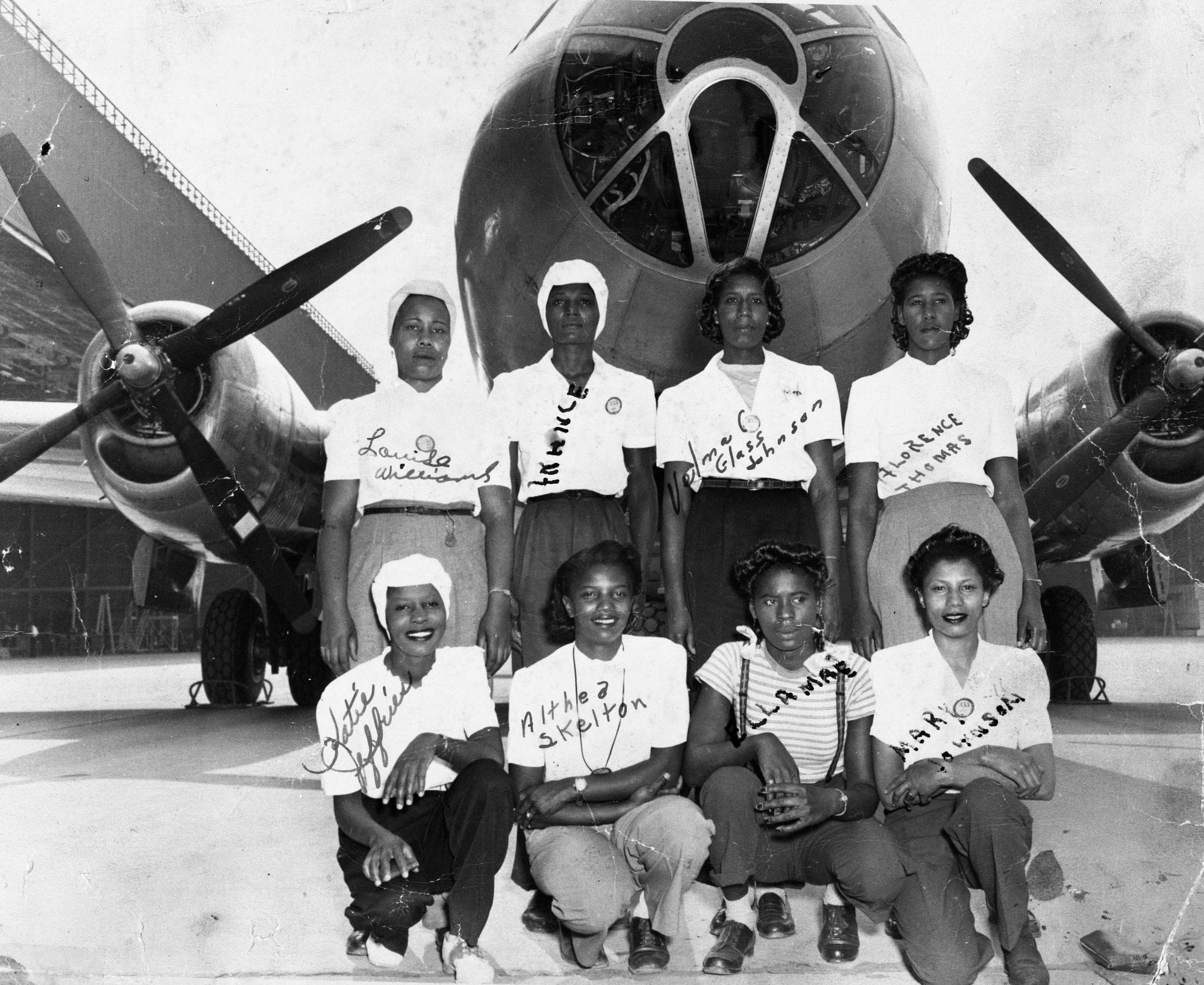 Photo of "black 'Rosies'" posing in front of an airplane
