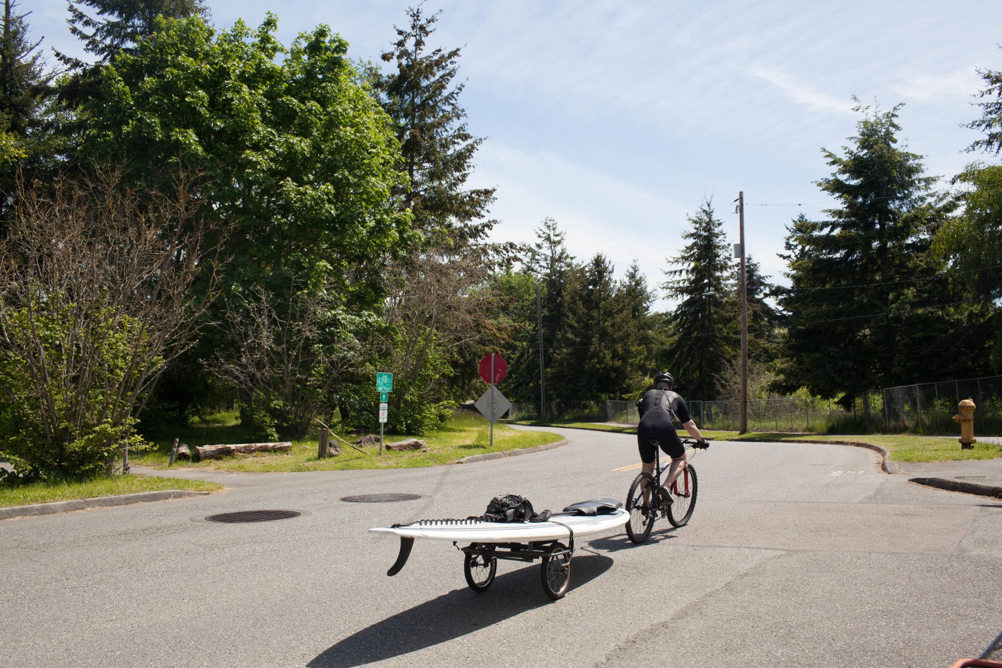 Man on a bicycle pulling his paddle board