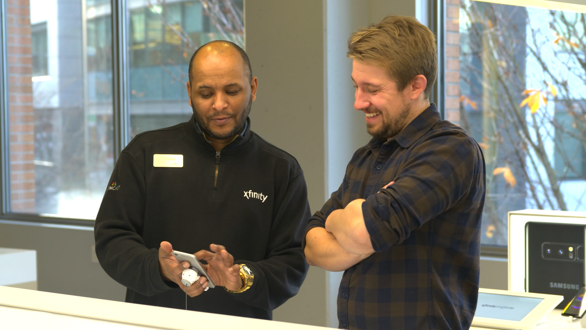An Xfinity employee shows a customer the features of a new cell phone.