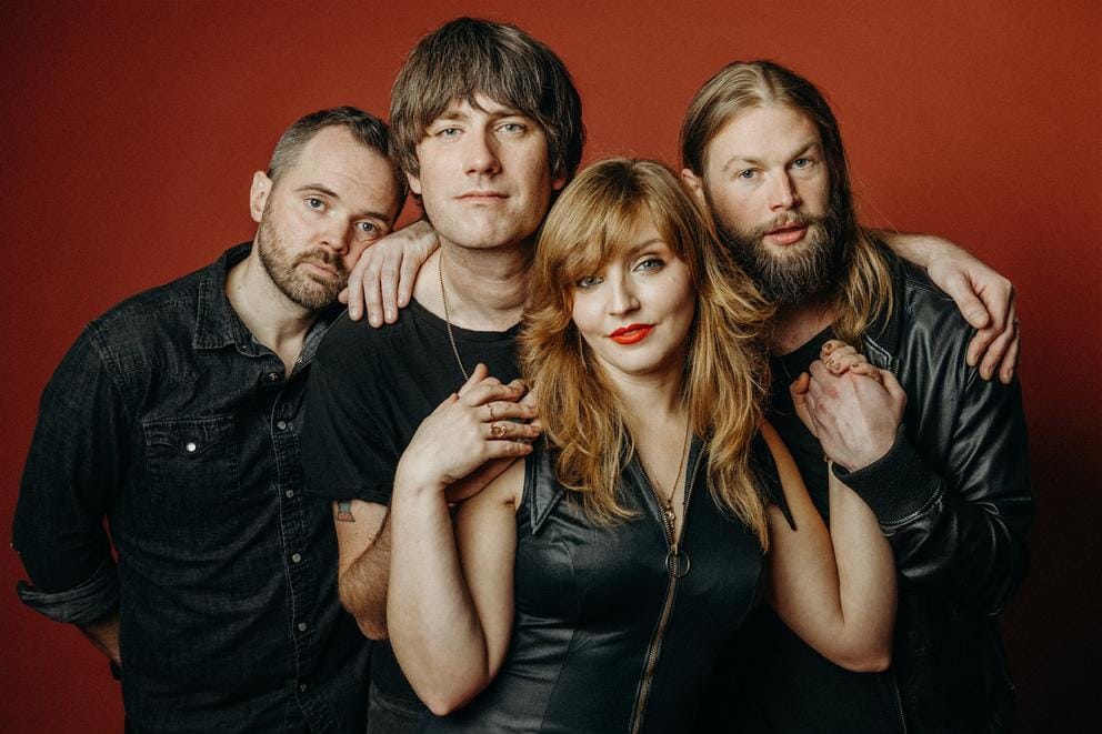 Four people looking at the camera on a red backdrop