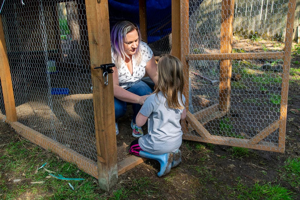 A woman hands a child a chicken