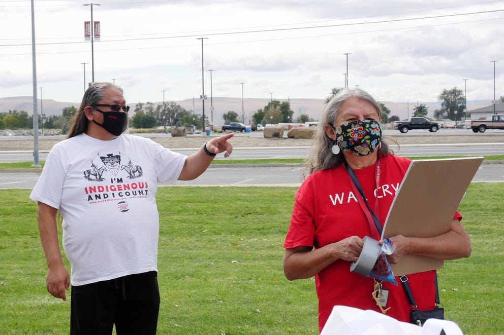 A man stands outside with a shirt that says I'm Indigenous and I count, while a woman stands next to him