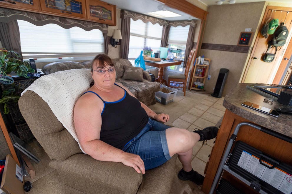 A woman sits in an armchair inside a trailer