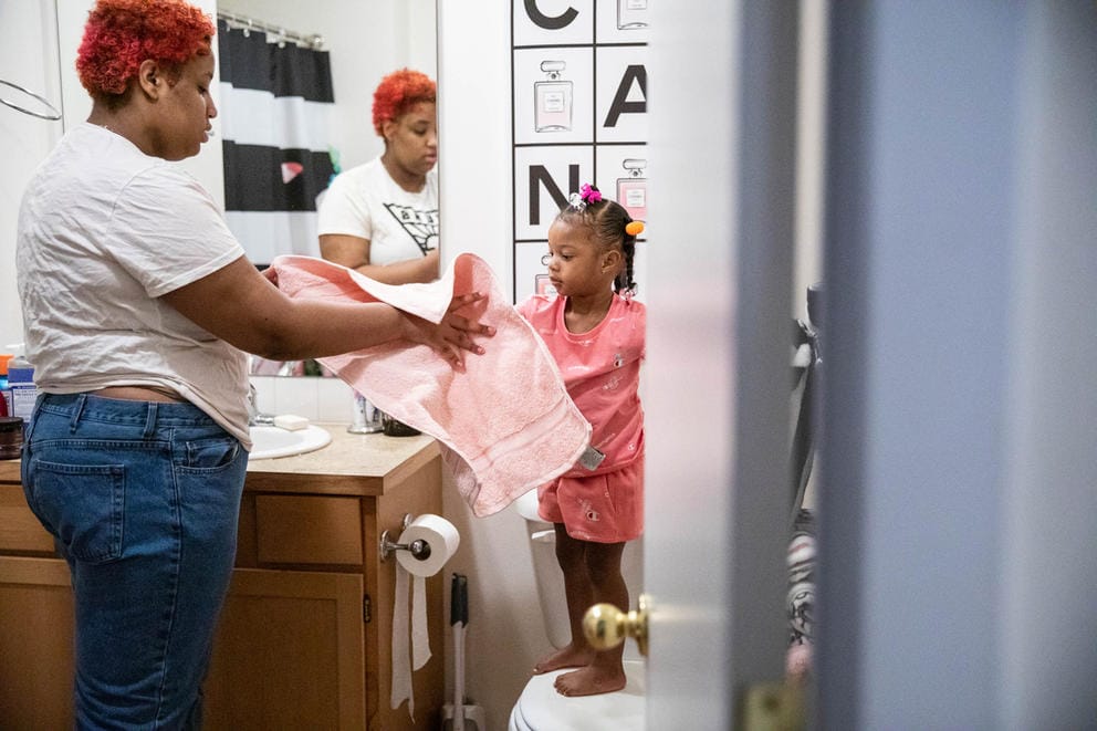 a young woman helps her toddler sister in the bathroom