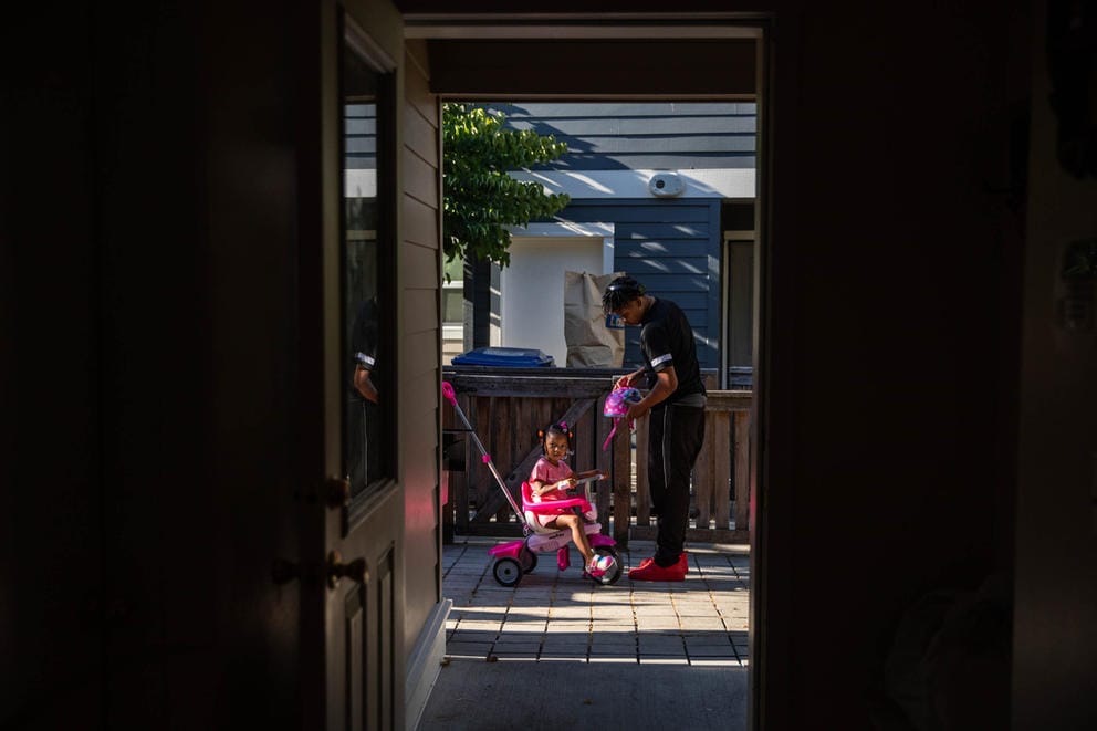 looking through a door to a young man playing with his kid sister