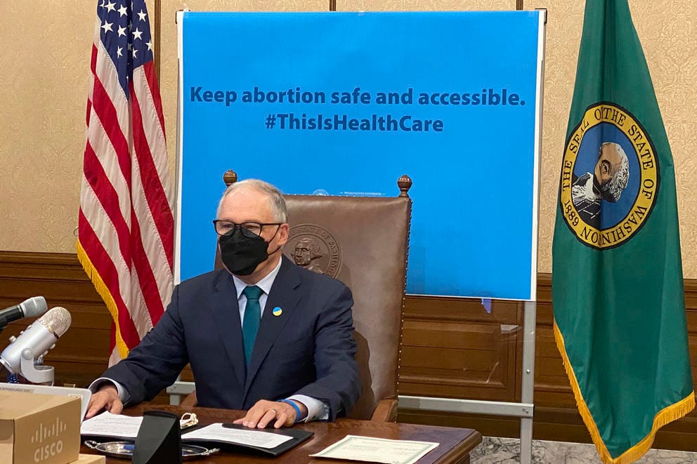 Jay Inslee sits while wearing a face masksa