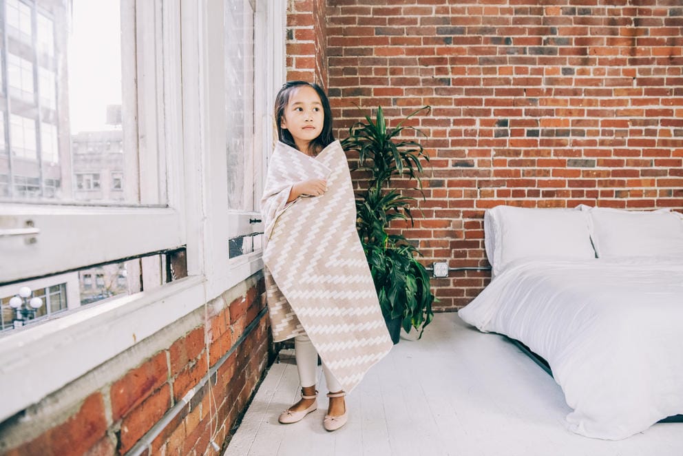 kid by window wrapped in blanket