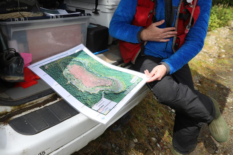 A person holds a map over a car bumper