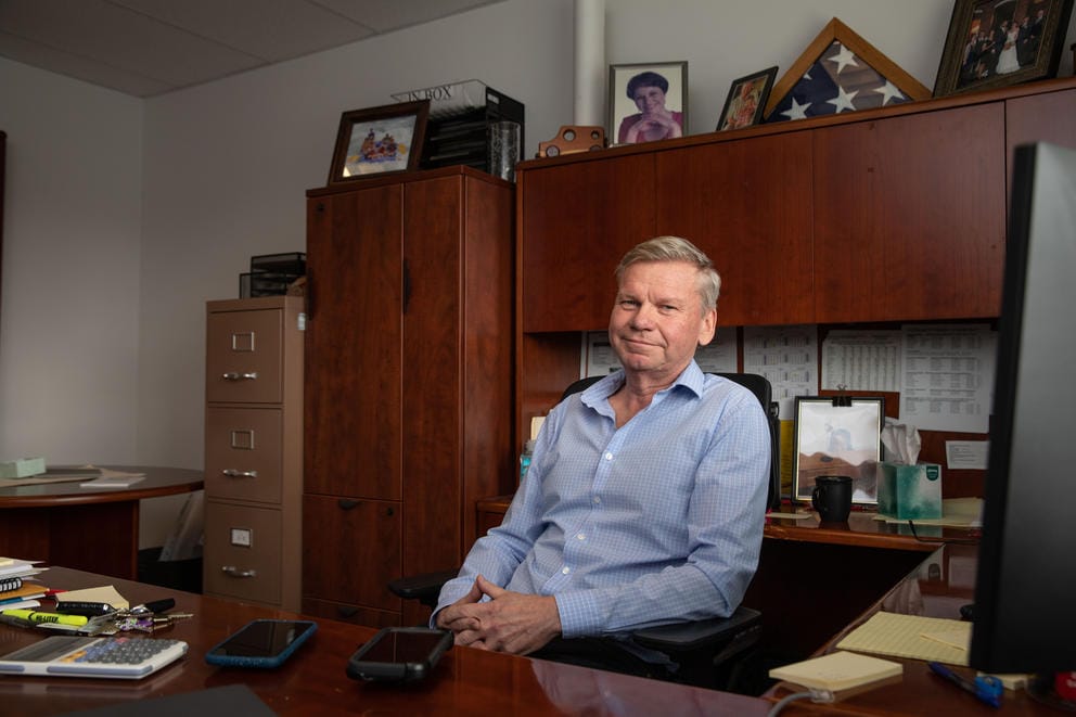 Brier's mayor Dale Kaemingk, in a light blue button-up shirt, sits behind a dark wooden desk with his hands crossed.