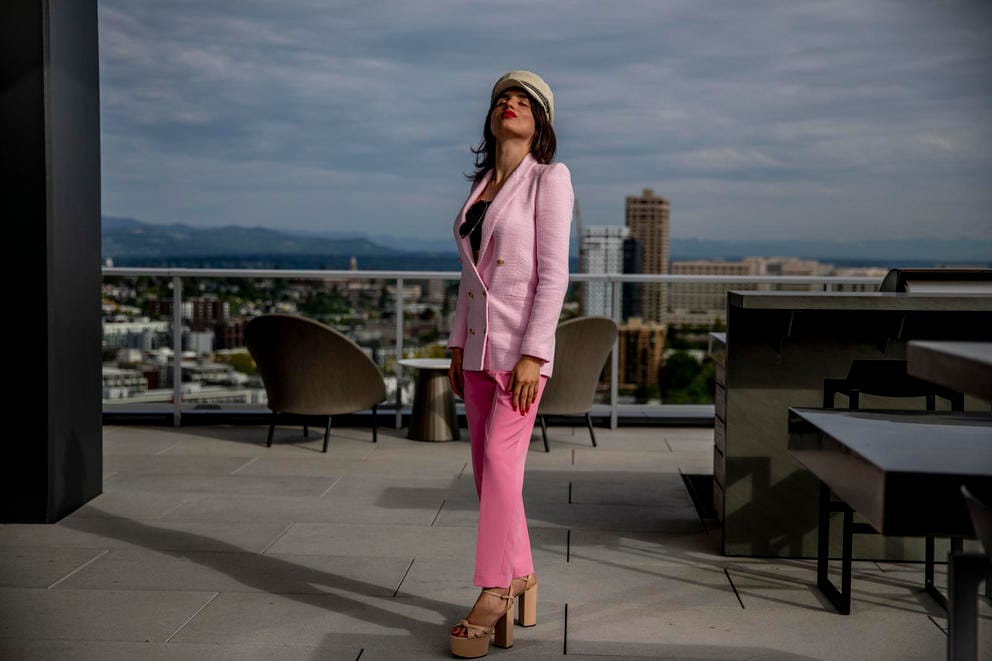 A woman poses with her head tilted back on a rooftop patio