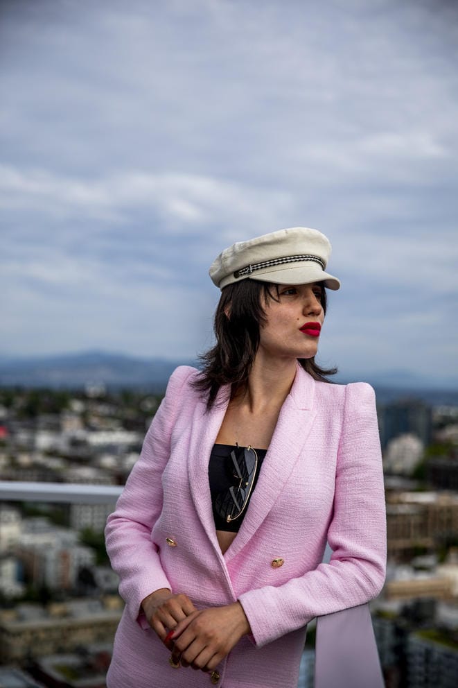 Venus Aoki looks into the distance, her hands together and elbow resting on a railing