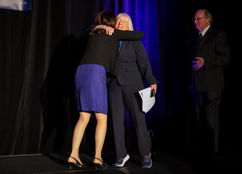 Two women embrace on stage
