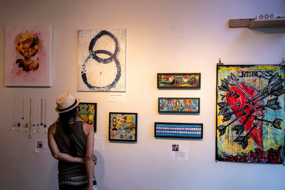 Person stands in front of a wall with works of art on it