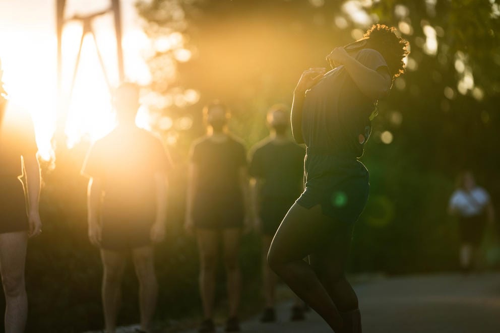 Person dances as the setting sun illuminates the photo from the left upper corner