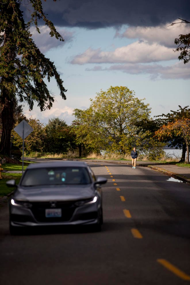 a car on a street next to a person walking in the street