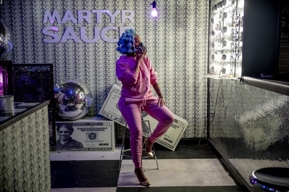 Person in pink outfit in art installation featuring $20 dollar bills with Harriet Tubman's face on it