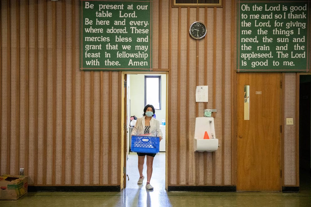 A food bank employee hauls food in a blue box into a staging area.