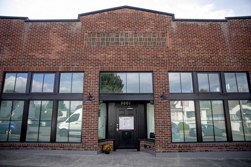 Brick building with six large windows, black door in the middle