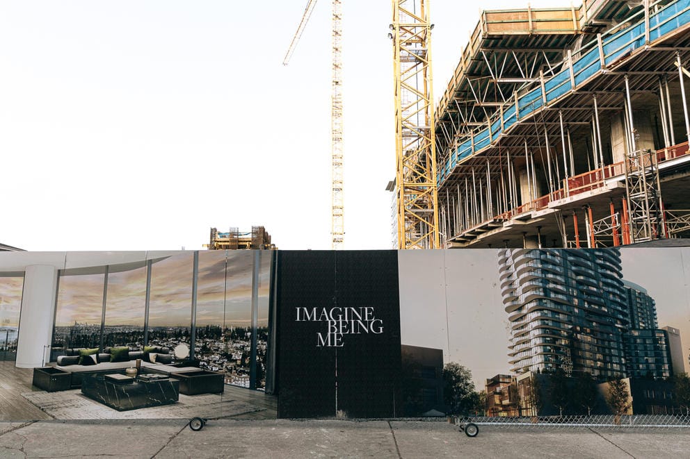 Advertisement wall surrounding an apartment building under construction reads