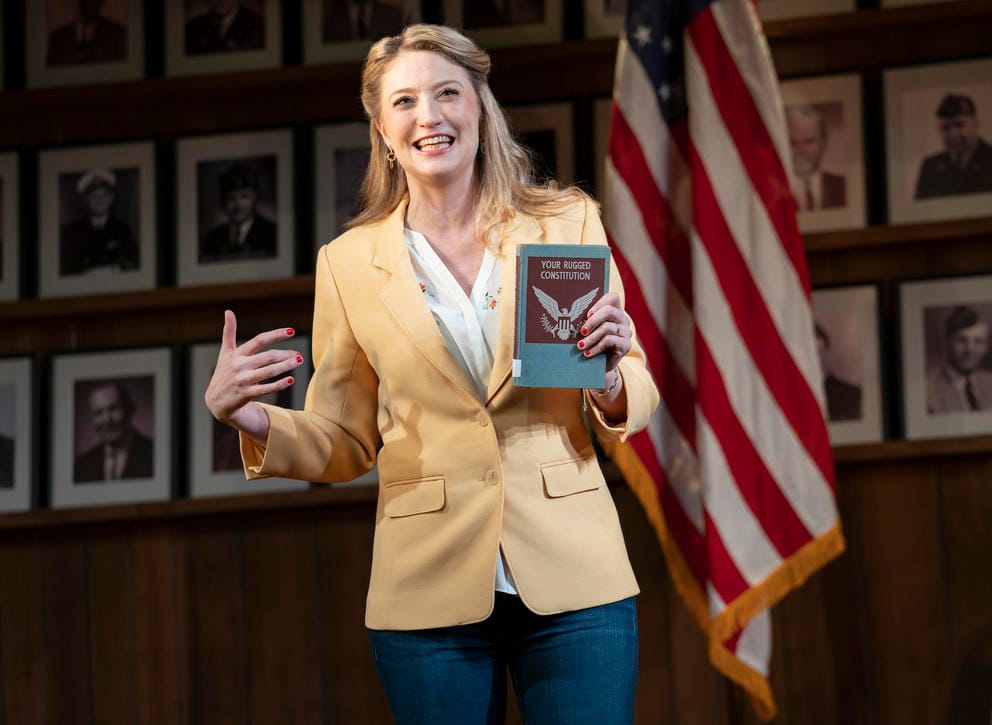 person in yellow blazer holds a book that says