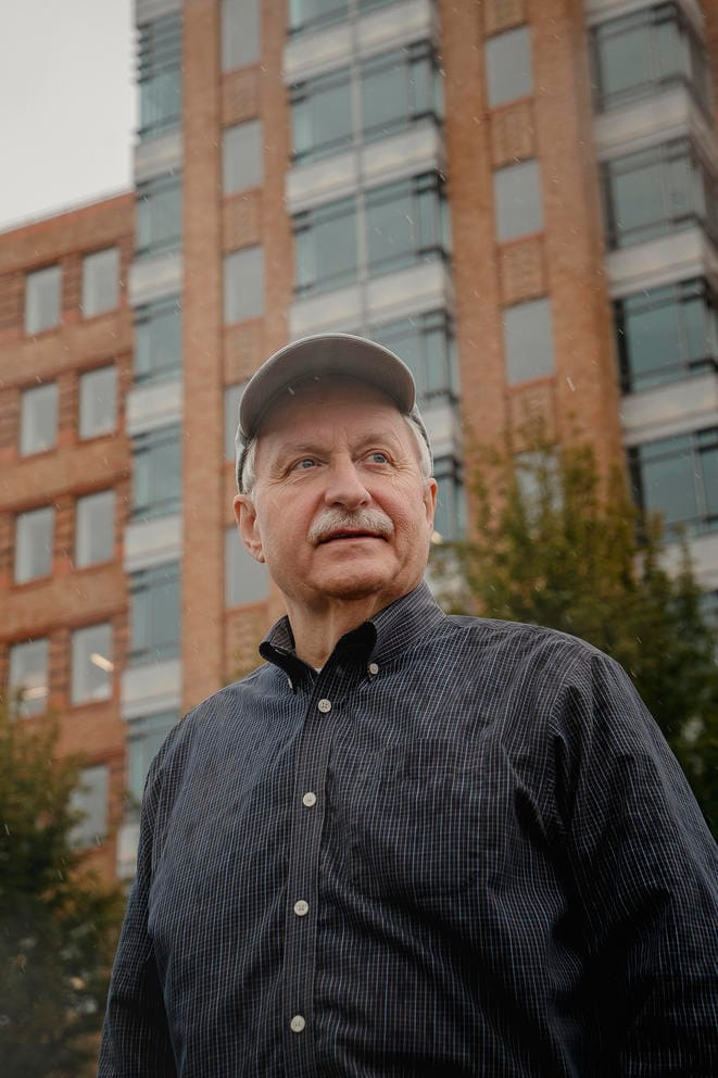 Man stands in front of tall brick building