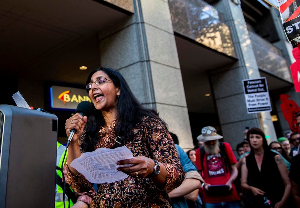A woman holding a microphone speaks in front of a crowd