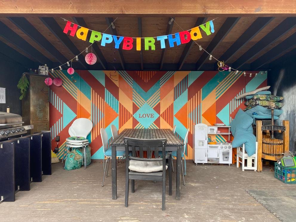 an outdoor dining table with a mural behind it, orange and turquoise stripes pointing to the word love