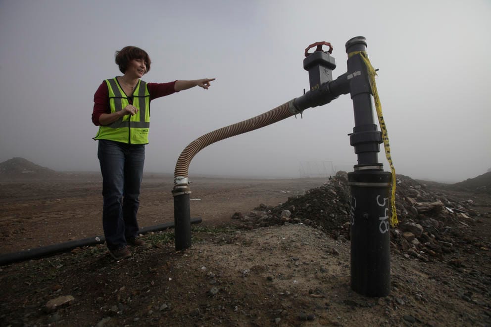 Landfill manager standing near a pump bringing up methane gas.