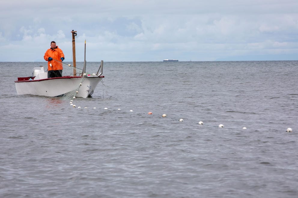 A man on a fishing boat puts out a net