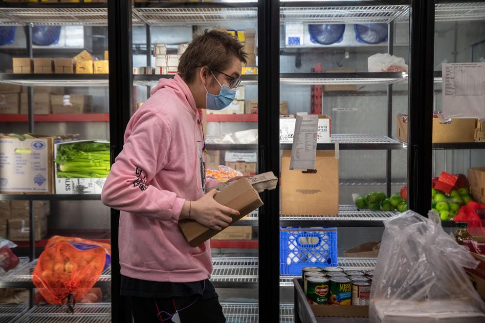 A person carries a box through an aisle of freezers