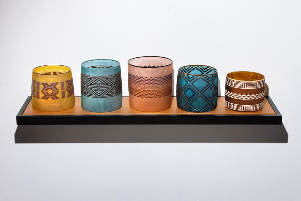 five glass baskets on a wooden shelf
