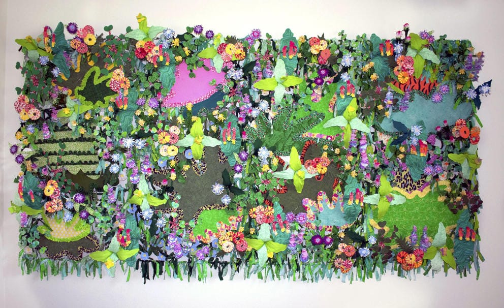 A collage fabric jungle wall with different types and colors of flowers, leaves and greenery as well as patches of animal patterns like tiger stripes and cheetah print.