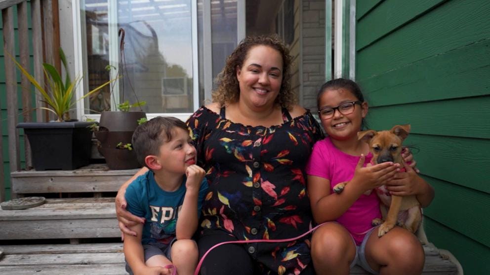 A woman sits on a step with two young children