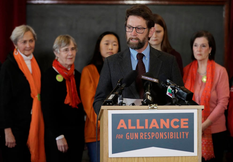 A person speaks at a podium with a sign that says