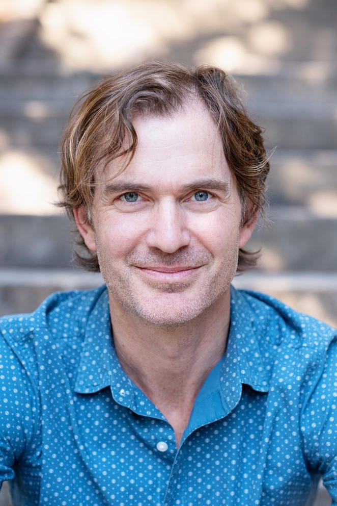 chest-up photo of a man facing the camera and smiling with his mouth closed