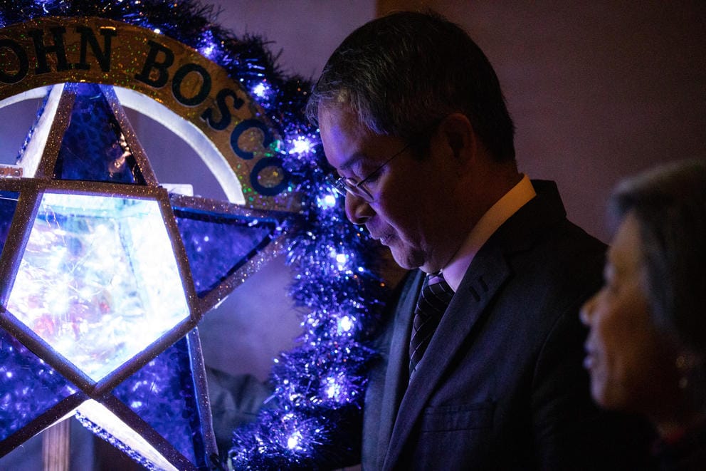 A man's face is lit up blue by a glowing lantern