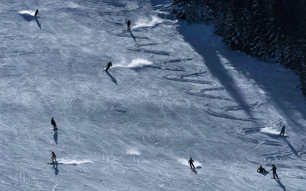 Skiers and snowboarders going down the slope