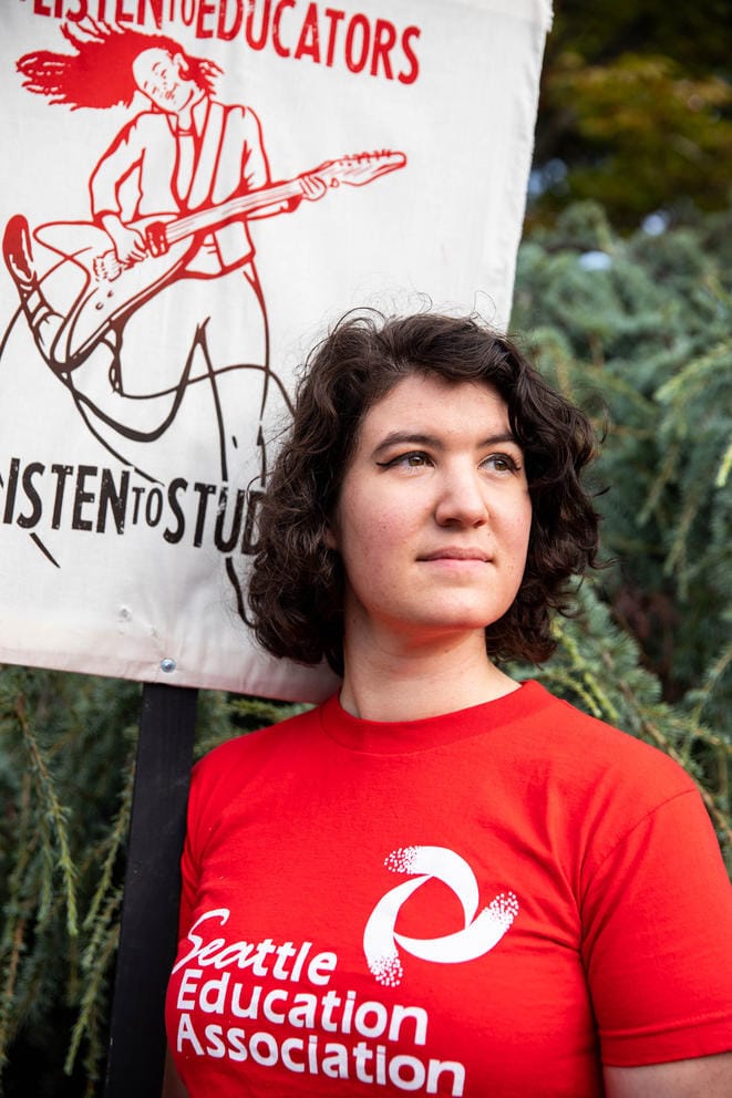 A teacher wears a red T-shirt that says