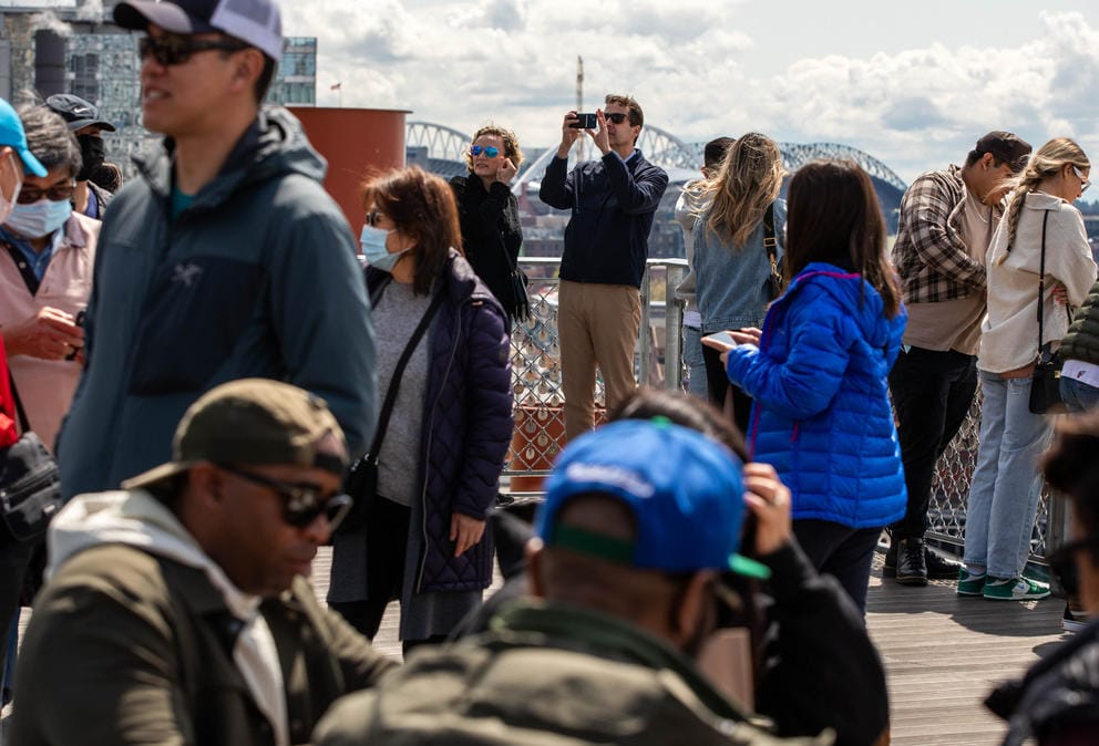 a crowd of people, some taking photos with their phones