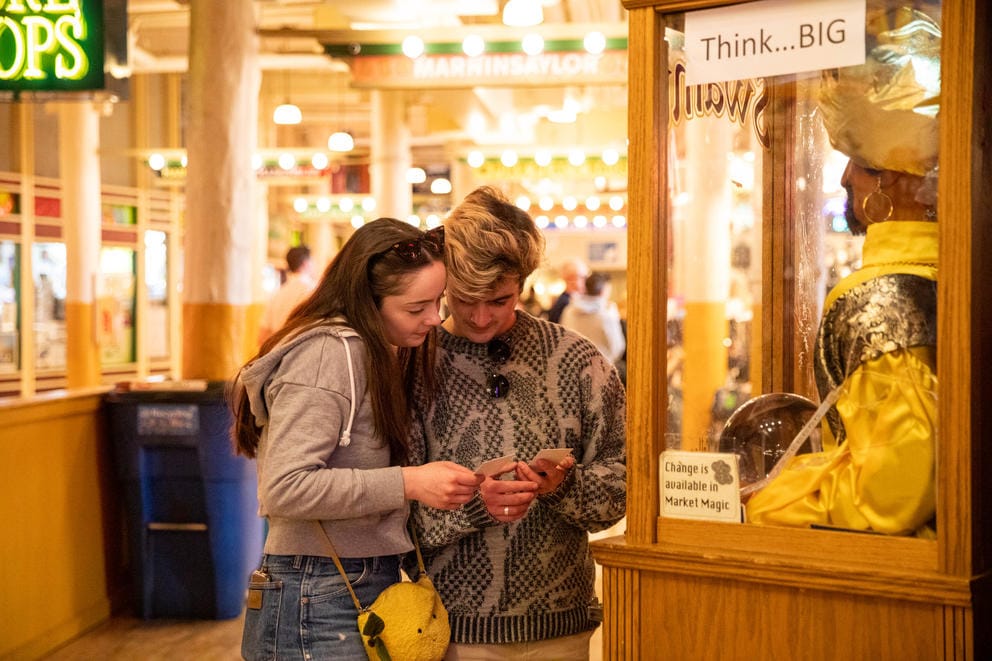 two people stand in front of a fortune teller machine