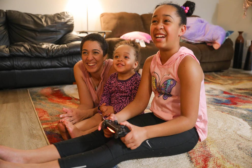 Sequoia Dolan and her daughters Zayah, 2, and Jaeleah, 10, play video games at home before dinner.