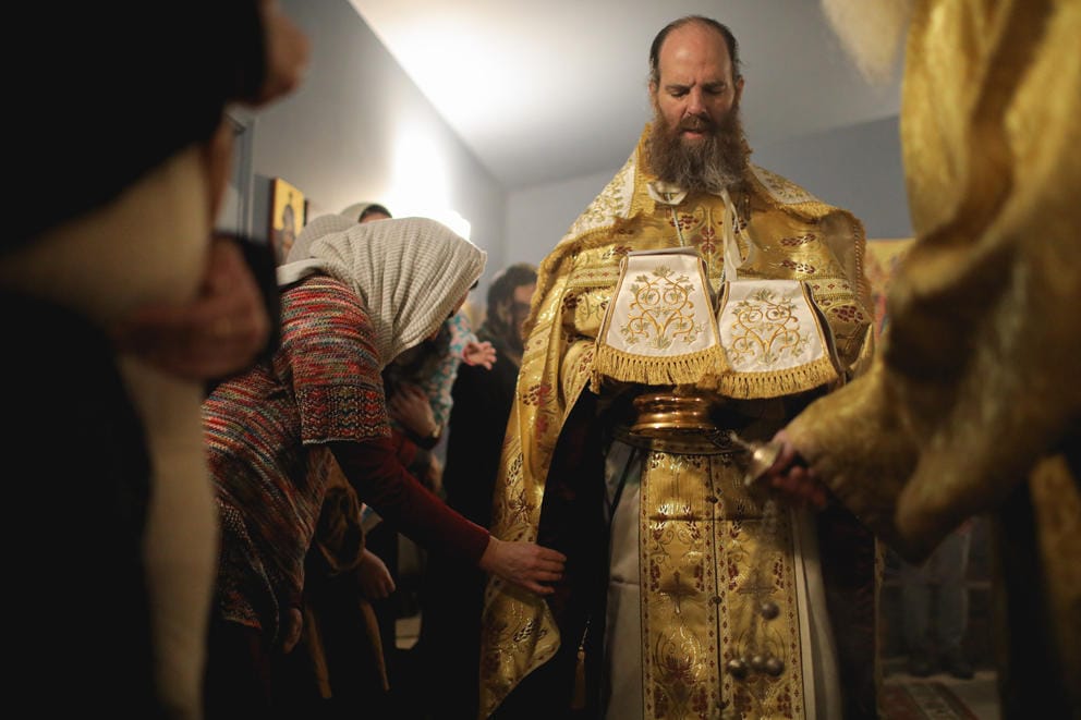 Parishoners touch the vestments of Father David Sommer and he prays over the eucharist