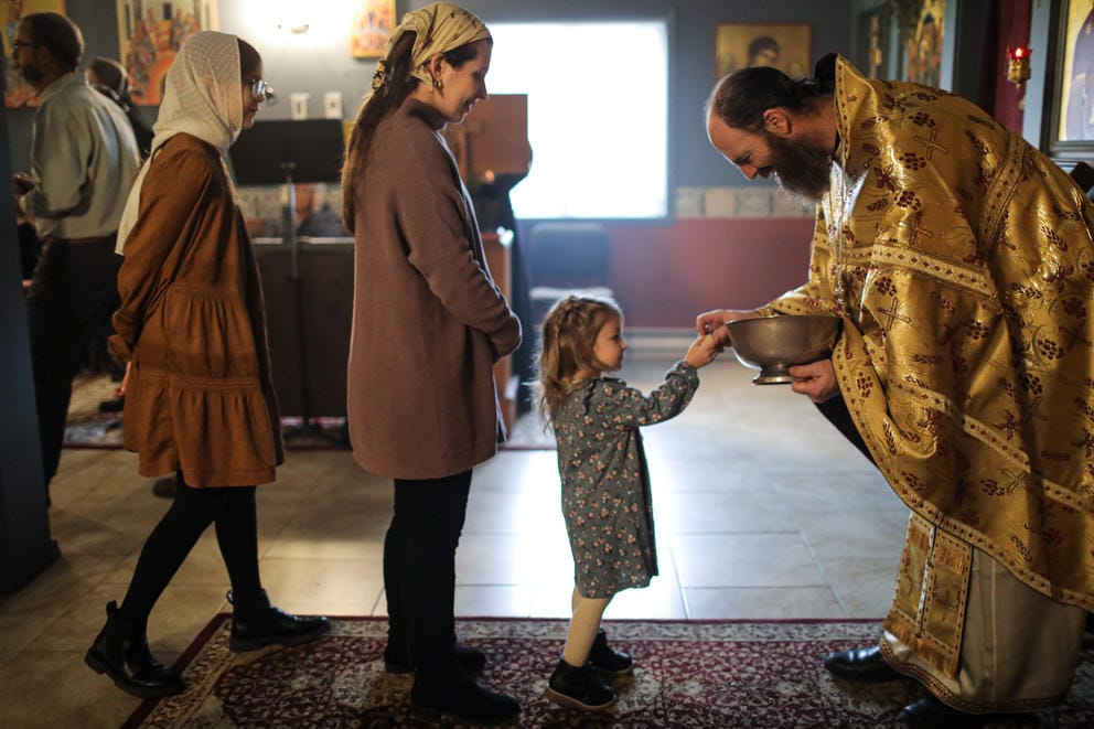 A child and others line up to receive the eucharist from a priest